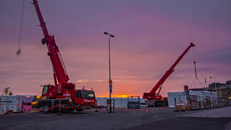 Time-lapse-shot-of-working-trucks-with-crane-on-construction-site-in-Slottsholmen-during-beautiful-sunrise-in-backdrop---Sweden,Europe
