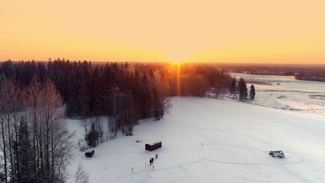 Luftbild,-Das-Die-Familie-Zeigt,-Die-Während-Des-Goldenen-Sonnenuntergangs-Am-Horizont-Auf-Einem-Verschneiten-Winterweg-Im-Wald-Spazieren-Geht
