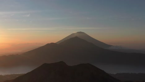 Magical-morning-view-of-volcano-silhouettes-in-Bali,-aerial