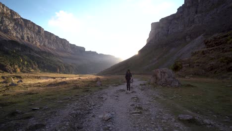 front-view-of-young-male-hiker-walking-towards-the-sun-in-Ordesa-Valley-national-park,-pyrenees,-huesca,-Spain