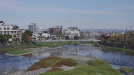 Kamo-River-on-Warm-Clear-Day,-Kyoto-City-in-Background,-Japan