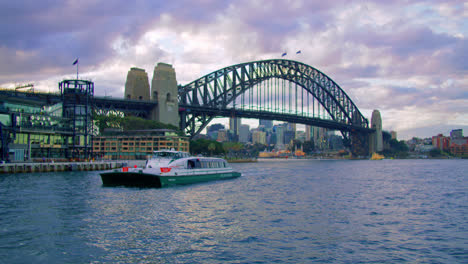 Boat-Passing-The-Harbour-Bridge-In-Sydney,-Australia-On-A-Cloudy-Day---wide-shot