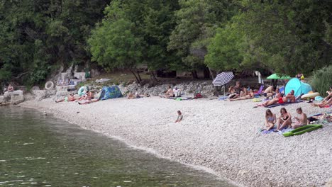 People-relax-on-pebble-beach,-Medveja,-Croatia