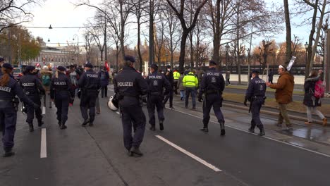 Panning-view-over-Police-officers-marching-behind-Corona-Protestors-in-Vienna,-Austria