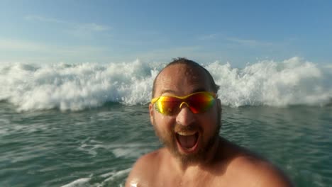 Active-man-having-fun-splashing-with-big-sea-waves-breaking-on-his-head