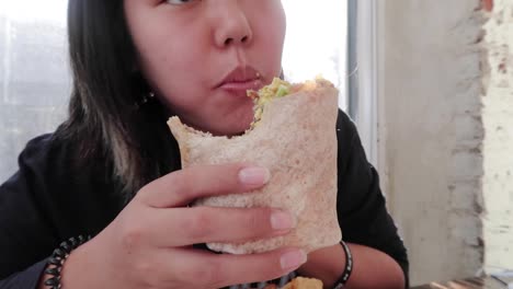 Vegan-Girl-Eating-Take-A-Big-Bite-of-A-Veggie-Burrito