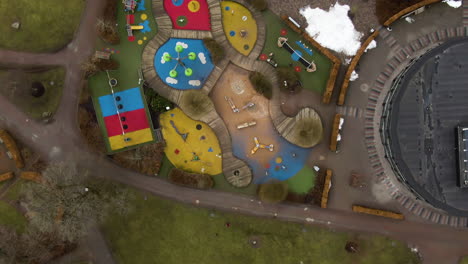 Colorful-playground-in-Swedish-town-park-on-moody-winter-day,-aerial-top-down-view