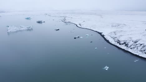 Aerial-backwards-shot-of-melting-icebergs-on-glacial-lake-of-Iceland---Climate-change-and-global-warming-on-earth