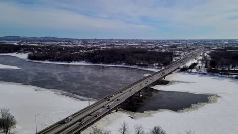 Cars-Driving-on-Bridge-over-Frozen-and-Snowy-River-on-Cold-Winter-Day