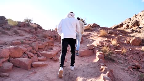 Two-guys-hiking-up-red-rock-stairs-in-the-desert