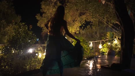 Schöne-Frau-Tanzt-Mit-Ihrem-Kleid-In-Einem-Beleuchteten-Waldgarten-Auf-Korfu,-Zeitlupe