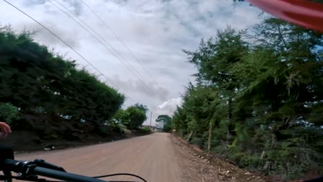 Two-bicyclists-ride-their-bicycle-on-a-road-inside-of-a-forest,-hill,-and-village-in-Guatemala,-North-America
