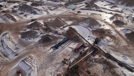 Top-Down-View-Of-Gravel-Pit-With-Driving-Truck-and-Heavy-Mining-Machinery---Dolly-In-Shot