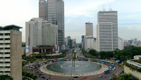 Massie-roundabout-with-heavy-traffic-and-skyscrapers-in-downtown-Jakarta,-aerial-drone-view