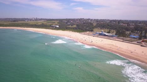 Long-Pull-back-aerial-shot-of-Maroubra-Beach-in-Sydney,-Australia-revealing-the-beautiful-coastal-shore-of-the-eastern-suburb-part-of-town