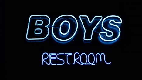 Jungentoilette-Badezimmer-Blaue-Leuchtreklame-An-Der-Wand-Geradeaus-Weitwinkelaufnahme,-Während-Die-Kamera-Langsam-Mit-Einem-Peitschenpfannenübergang-Heranzoomt---Im-Kino-4k