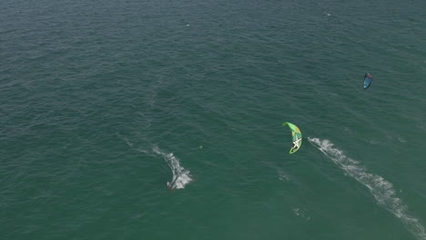 Aerial:-Kite-surfers-ride-in-opposite-directions-on-choppy-green-sea