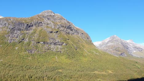Impressive-Norwegian-mountains,-green-forest-valley,-blue-sky