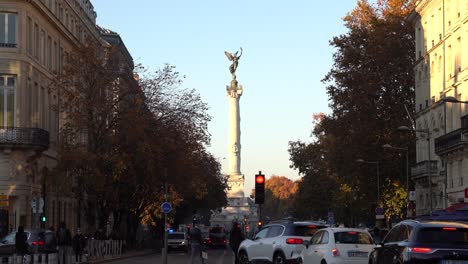 July-30th-avenue-overlooking-the-Girondins-monument-column-with-vehicle-and-people-traffic-on-an-autumn-day,-Handheld-shot