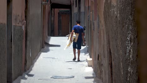 Boy-walking-down-an-alley-in-Marrakesh-Morocco-African,-handheld-drifting-shot
