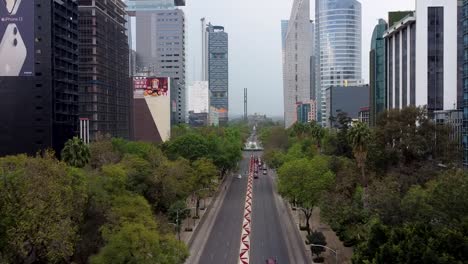 Aerial-View-Along-Paseo-de-la-Reforma-Approaching-the-Diana-Cazadora-Roundabout,-with-a-View-of-the-Skyscrapers-and-Chapultepec-Castle-in-the-Background,-Mexico-City
