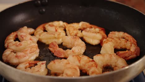 Delicious-shrimps-browning-on-hot-oil-pan,-chef-using-tongs-to-grab-and-flipping-sides-and-sauteing-the-tasty-prawns-until-it-is-seared-in-golden-brown,-close-up-shot-of-healthy-meal-preparation