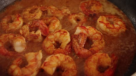 Fresh-and-delicious-prawns-soaking-in-the-bubbling-sweet-paprika-sauce,-slowly-cooking,-absorbing-and-thickening-in-shallow-frying-pan,-extreme-close-up-shot