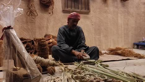 Fisherman-making-rope-with-dried-palm-leaves,-it-is-a-traditional-occupation-in-Arab-countries-and-a-part-of-arabic-culture