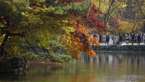Group-of-People-in-masks-take-pictures-near-stone-pagoda-of-Chundangji-pond-in-Autumn,-Changgyeonggung-Palace,-covid-19,-Seoul-South-Korea