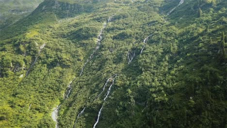 drone-shot-flying-towards-with-the-camera-tilting-down-over-a-couple-of-waterfalls-on-the-side-of-a-mountain-in-Switzerland-in-4k