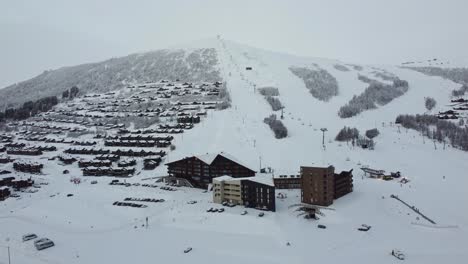 Myrkdalen-hotel-and-apartment-buildings-with-skilift-running-in-background---Early-morning-forward-moving-aerial-at-winter-season-with-people-skiing