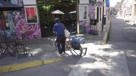 Tracking-shot-of-man-pushing-his-bike-through-streets-of-Palermo,-Buenos-Aires