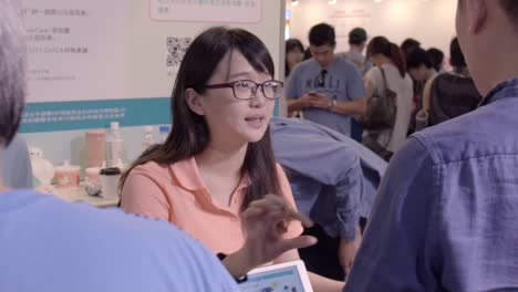 Asian-woman-using-her-hands-to-explain-something-technical-at-technology-expo