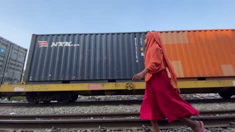 Cargo-Containers-Transportation-On-Freight-Train-Going-Past-With-Young-Muslim-Girl-Walking-Past