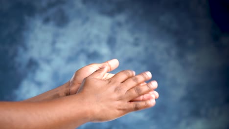 Adult-african-female-hands-rubbing-and-moisturizing-on-a-blue-background