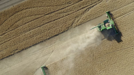 Aerial-rise-directly-above-combine-harvesting-grain-in-Saskatchewan,-Canada