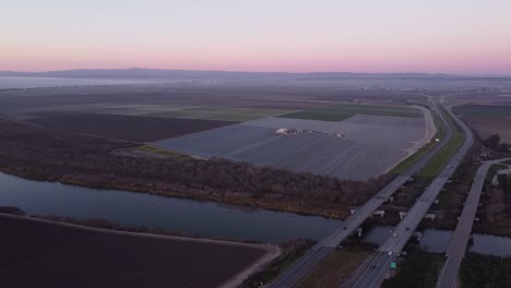 Highway-1-passing-over-Salinas-river-near-Castroville,-agriculture-fields-all-around,-high-angle-drone-view