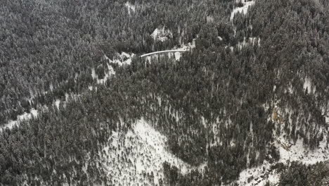 Flying-over-snowy-mountain-forest-towards-a-viaduct