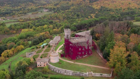 Beautiful-Castle-of-Celsa-in-Tuscany-with-red-colored-vines-growing-on-wall,-aerial