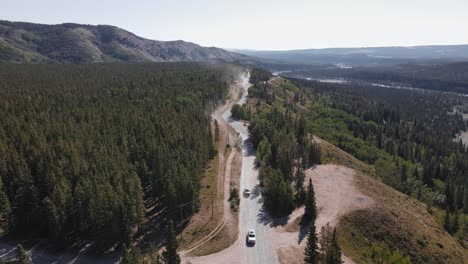 Multiple-cars-driving-along-a-dusty-logging-road-that-leads-through-boreal-forests-in-the-outskirts-of-the-Rocky-Mountains