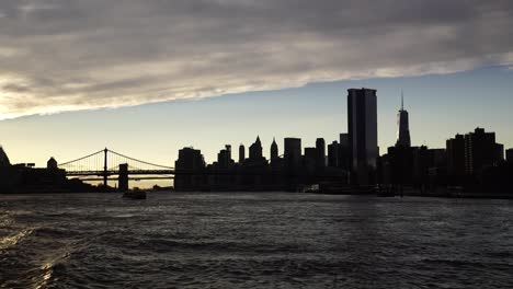 Silhouette-of-New-York-city-and-bridge-during-sunset,-view-from-Hudson-river