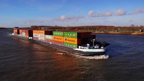 Aerial-Starboard-And-Forward-Bow-View-Of-Millennium-Ship-Carrying-Cargo-Containers-Along-Oude-Maas