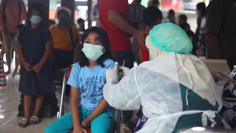 Yogyakarta,-Indonesia---Dec-20,-2021-:-an-elementary-school-girl-wearing-a-mask-is-receiving-the-covid-19-vaccine