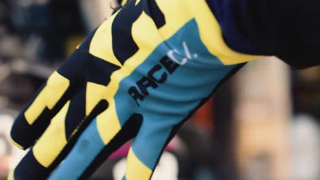 Hand,-Die-In-Zeitlupe-Einen-Dünnen-Blauen-Und-Gelben-Motocross-Handschuh-Anzieht