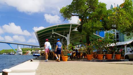 Tourists-visiting-a-cafe-on-the-waterfront-of-Saint-Anna-Bay-in-the-city-of-Punda,-Willemstad,-on-the-Caribbean-island-of-Curacao