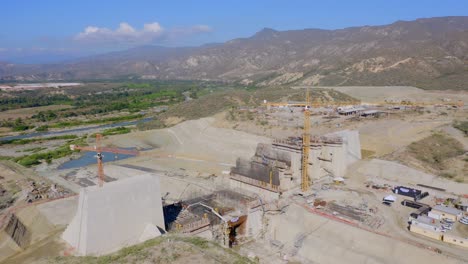 Wide-Aerial-View-of-Cranes,-Steel-and-Concrete-Wall-Structure-under-Construction-of-Unfinished-Presa-Monte-Grande-Dam-and-Floodgate,-Dominican-Republic
