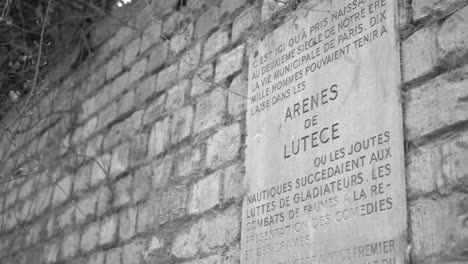 Sign-On-The-Brick-Walls-At-The-Roman-Ancient-Amphitheater-Of-Arenas-of-Lutetia-In-Paris,-France