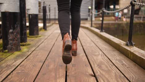 shot-of-woman-leg's-on-heels-walking-in-a-dock-in-Bristol-passing-a-bridge