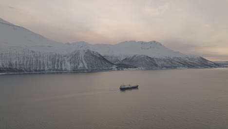Freighter-Shipping-Commercial-Cargo-In-Snowy-Fjord-Landscape,-Aerial