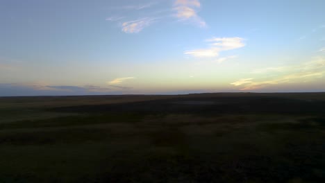 Rückwärtsflug-Bei-Sonnenuntergang-Mit-Whiskyfarbenen-Wolken-Und-Schattiger-Erde-Darunter